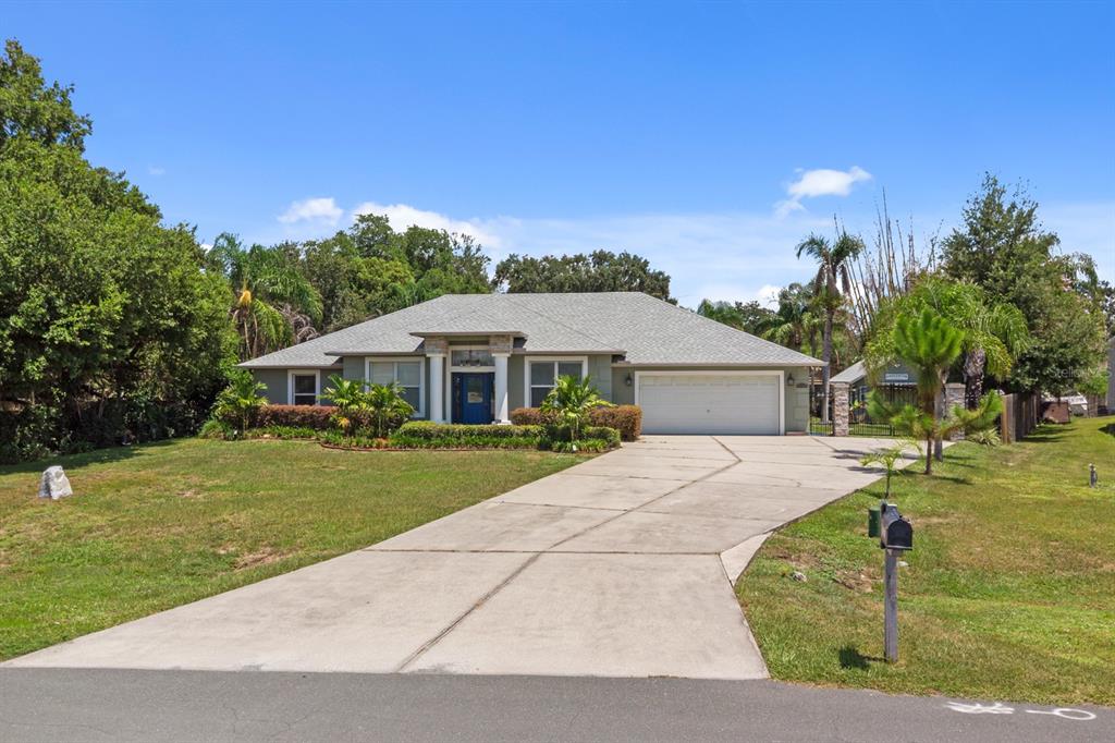 A single-story house with a gray roof, tan siding, and a concrete driveway — 1910 LEE WOOD COURT, ST CLOUD, FL
