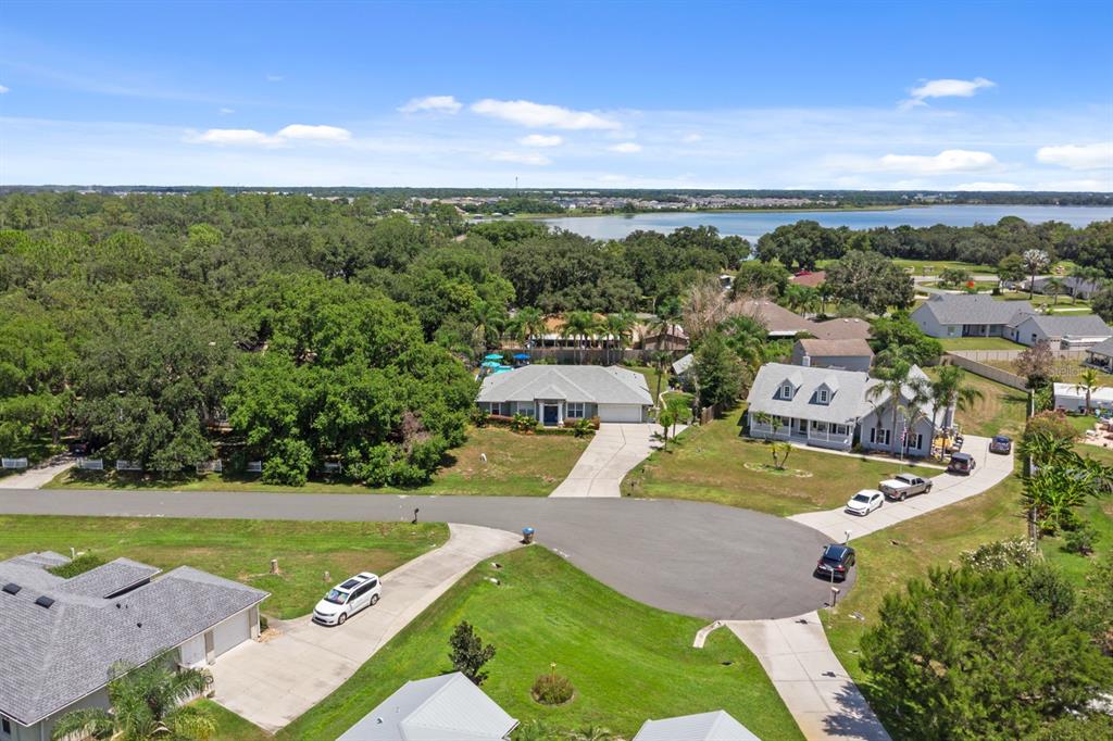 An aerial view shows several suburban houses with driveways, lawns, and trees near a lake — 1910 LEE WOOD COURT, ST CLOUD, FL