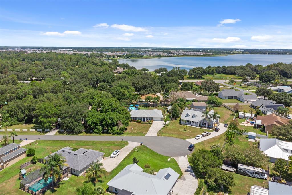 An aerial view shows a residential neighborhood with houses, driveways, trees, and a large lake — 1910 LEE WOOD COURT, ST CLOUD, FL
