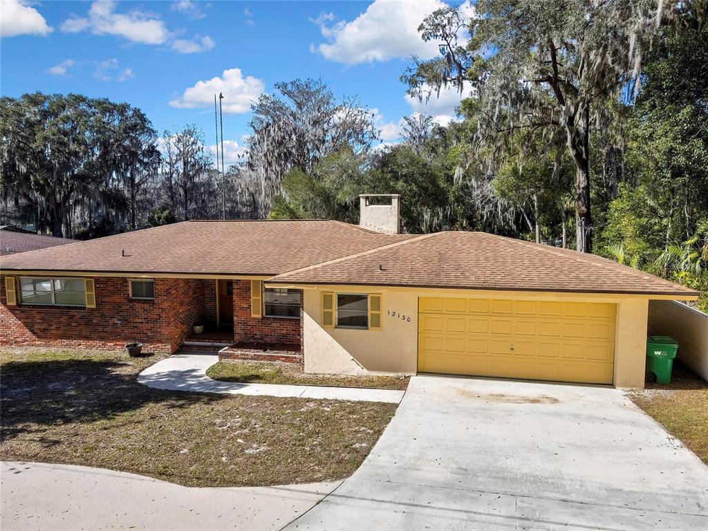 A single-story brick and stucco house features a yellow garage door and a shingled roof — 12130 MAPLE STREET, DUNNELLON, FL