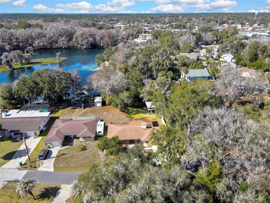 An aerial view shows two houses with brown roofs situated near a lake and trees — 12130 MAPLE STREET, DUNNELLON, FL