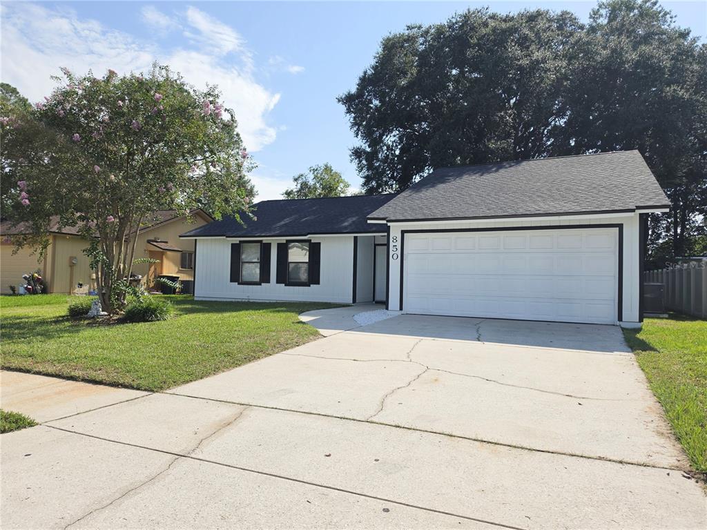 A single-story house with white siding, black shutters, and a two-car garage — 850 ARIES ROAD W, JACKSONVILLE, FL