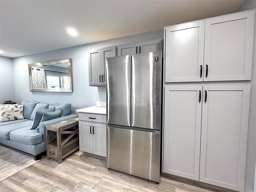 A kitchen area features light gray cabinets, a stainless steel refrigerator, and an adjacent sofa — 902 GIBBS ROAD UNIT 283, VENICE, FL
