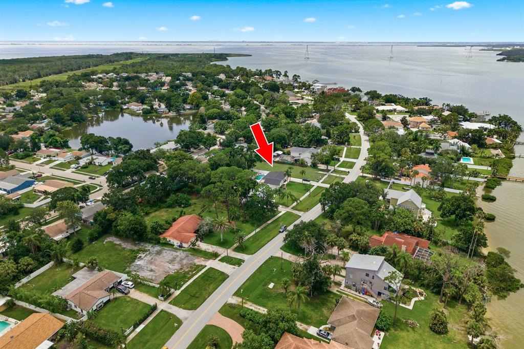 An aerial view shows a residential neighborhood with houses, trees, and a nearby body of water — 601 SHORE DRIVE E, OLDSMAR, FL