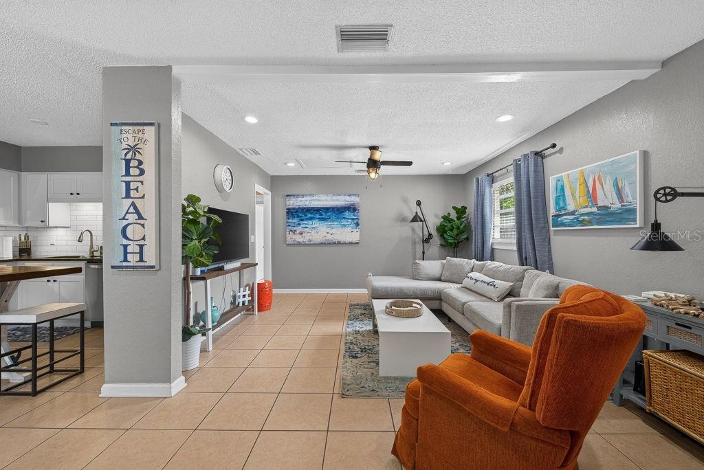 A living room features a sectional sofa, an orange armchair, and tile flooring — 610 1ST AVENUE NE, LARGO, FL