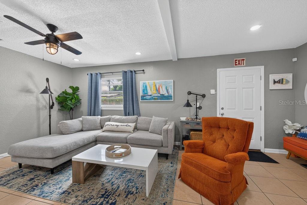 A living room features a grey sectional sofa, an orange armchair, and a white coffee table — 610 1ST AVENUE NE, LARGO, FL