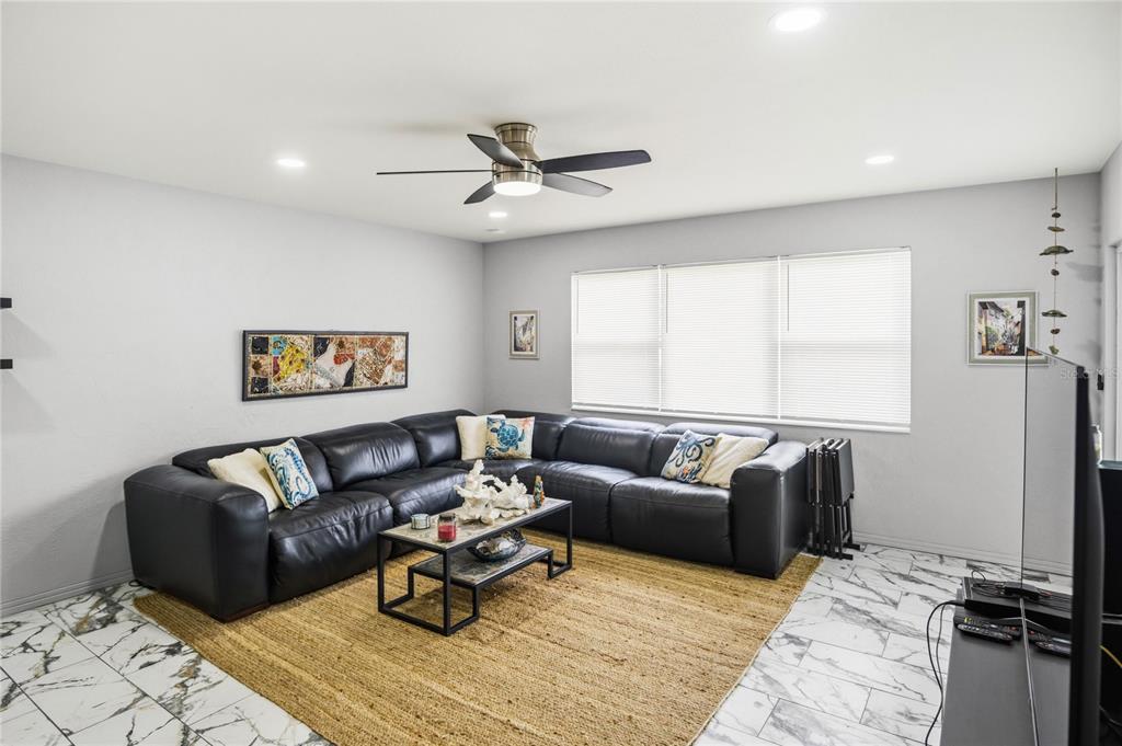 A living room features a black sectional sofa, a coffee table, and white marble flooring — 416 73RD AVENUE N UNIT 207, ST PETERSBURG, FL