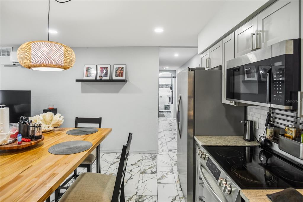 A dining area with a wooden table sits adjacent to a kitchen with stainless appliances — 416 73RD AVENUE N UNIT 207, ST PETERSBURG, FL