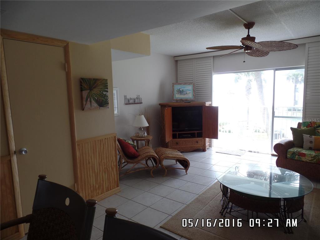 A living room features tile flooring, a ceiling fan, wicker furniture, and a sliding glass door — 815 OCEAN SHORE BOULEVARD UNIT 9A, ORMOND BEACH, FL