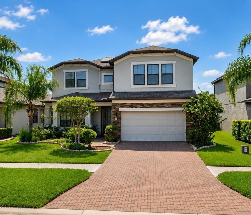A kitchen features a large granite-topped island, white cabinetry, stainless steel appliances, and blue backsplash — 19129 LONG LAKE RANCH BOULEVARD, LUTZ, FL