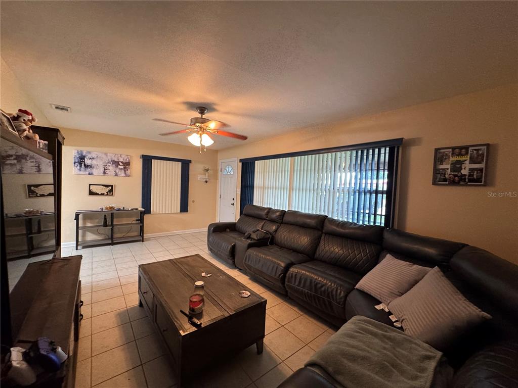 A living room features tile flooring, a large sectional sofa, and a ceiling fan — 519 THOMAS AVENUE, FROSTPROOF, FL