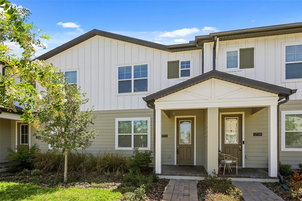 An open-concept living room features a sectional sofa, a round coffee table, and wood flooring — 17723 JAPONICA BLOOM DRIVE, WINTER GARDEN, FL