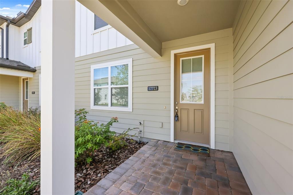 An open-concept living area features light wood-look tile flooring, white walls, and a kitchen island — 17723 JAPONICA BLOOM DRIVE, WINTER GARDEN, FL