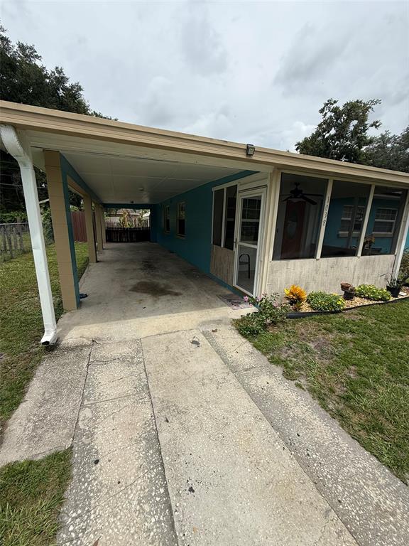 A grassy backyard features a swing set, a central tree, and a concrete driveway — 1038 CANAL DRIVE W, LAKELAND, FL