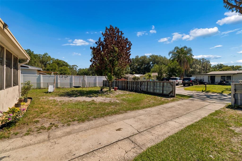 A covered porch features tiled flooring, two wicker chairs, a small table, and a ceiling fan — 1038 CANAL DRIVE W, LAKELAND, FL