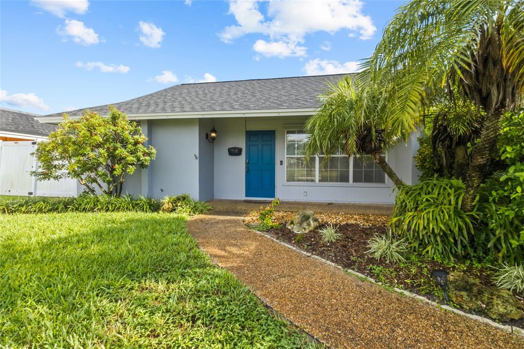 A single-story house with a blue front door, a gravel walkway, and a palm tree — 7303 11TH AVENUE W, BRADENTON, FL