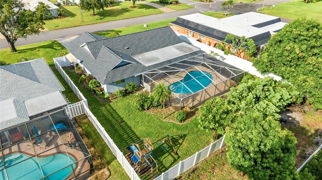 An aerial view shows a house with a screened pool, a fenced yard, and a playset — 7303 11TH AVENUE W, BRADENTON, FL