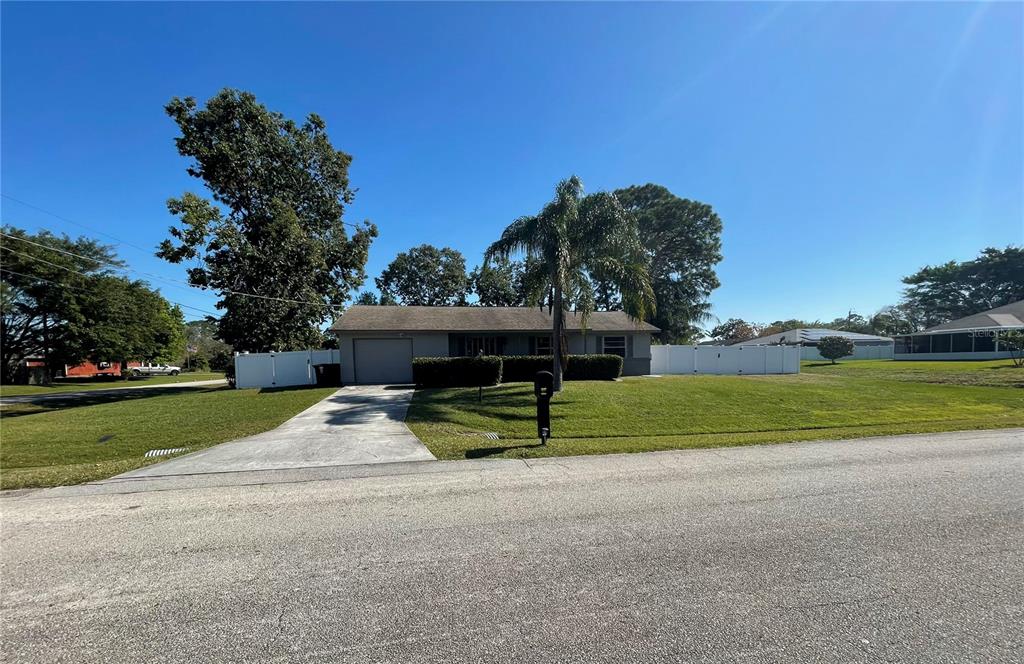 A single-story house with a concrete driveway, a palm tree, and a white privacy fence — 2081 SW GEMINI LANE, PORT ST LUCIE, FL