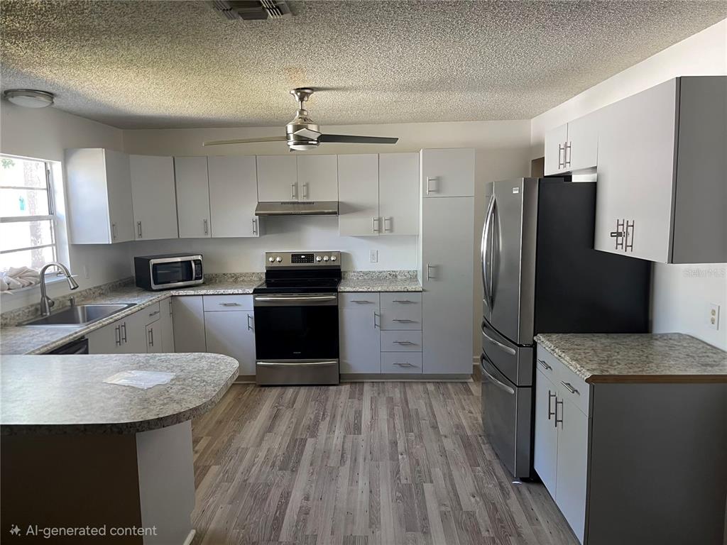 A kitchen features light gray cabinets, stainless steel appliances, and speckled laminate countertops — 2081 SW GEMINI LANE, PORT ST LUCIE, FL