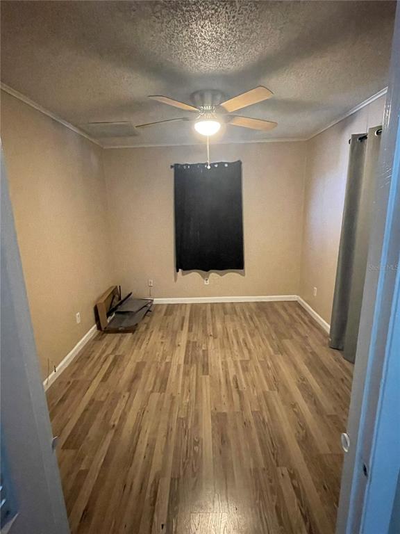 An empty bedroom features light wood-look flooring, beige walls, and a ceiling fan — 2081 SW GEMINI LANE, PORT ST LUCIE, FL