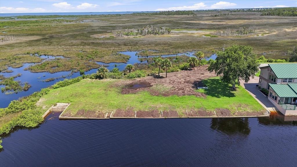 An aerial view shows a waterfront lot with a concrete seawall and adjacent house — 3190 INDIAN GULF LANE, HERNANDO BEACH, FL