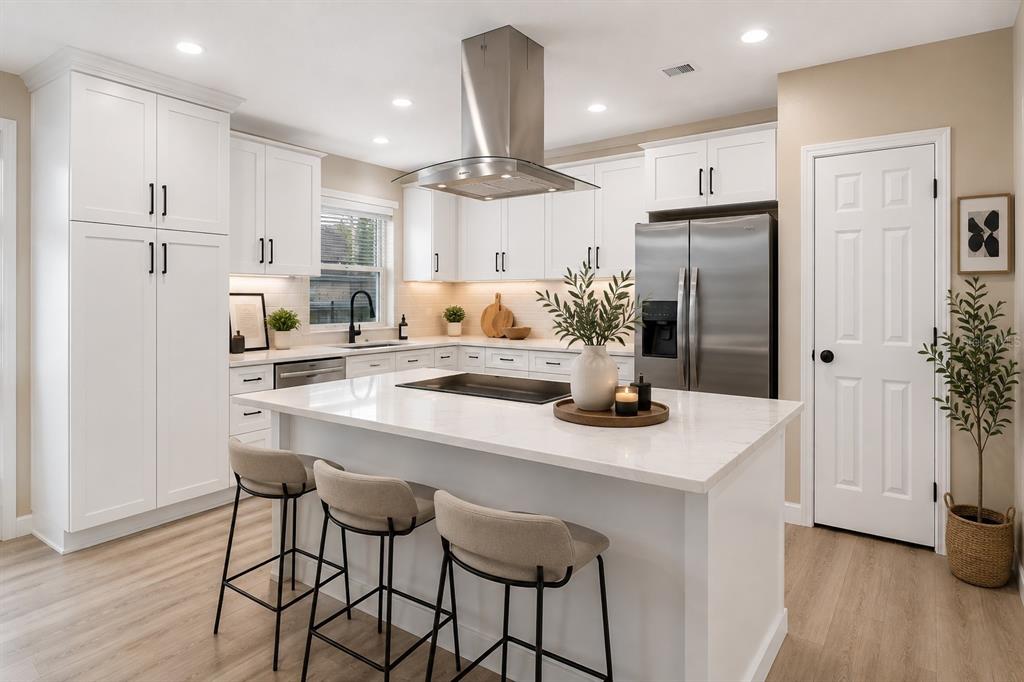 A modern kitchen features white cabinets, a central island, stainless steel appliances, and wood flooring — 217 ELLSWORTH DRIVE, KISSIMMEE, FL