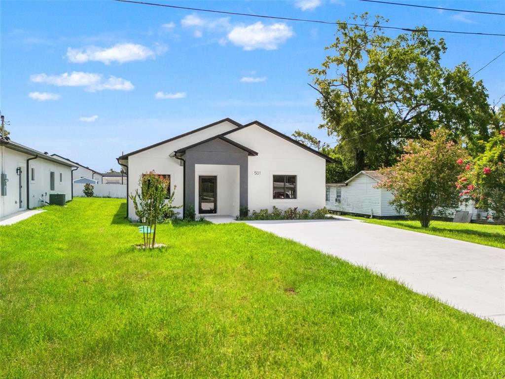 A modern, white single-story house with a dark gray entryway and a concrete driveway — 501 OCEAN AVENUE, APOPKA, FL