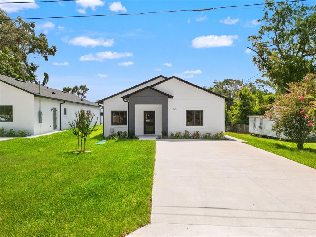 A modern, white single-story house with a grey entryway and a concrete driveway — 501 OCEAN AVENUE, APOPKA, FL