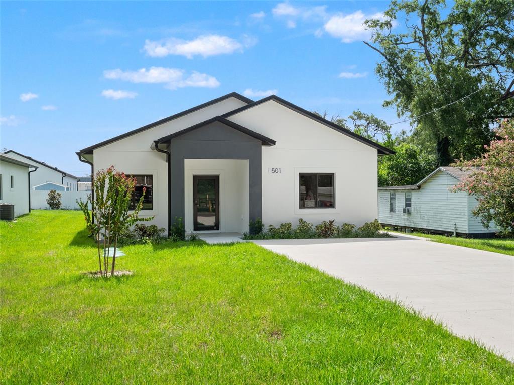 A modern, white single-story house with a dark gray entryway and a concrete driveway — 501 OCEAN AVENUE, APOPKA, FL