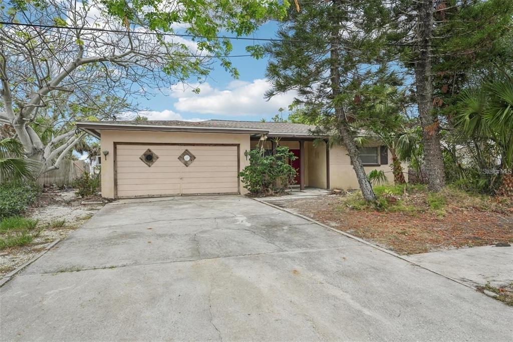 A single-story house with a beige exterior, a two-car garage, and a concrete driveway — 9300 GULF BOULEVARD, ST PETE BEACH, FL