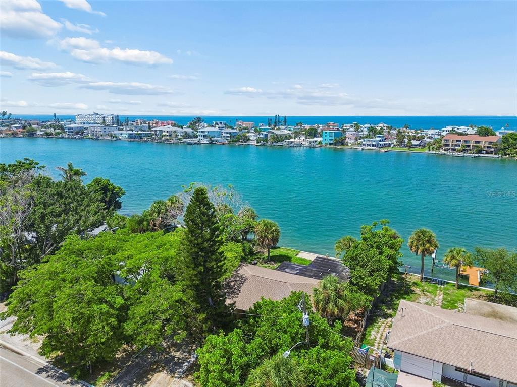 An aerial view shows a waterfront house surrounded by trees with a view of the ocean — 9300 GULF BOULEVARD, ST PETE BEACH, FL