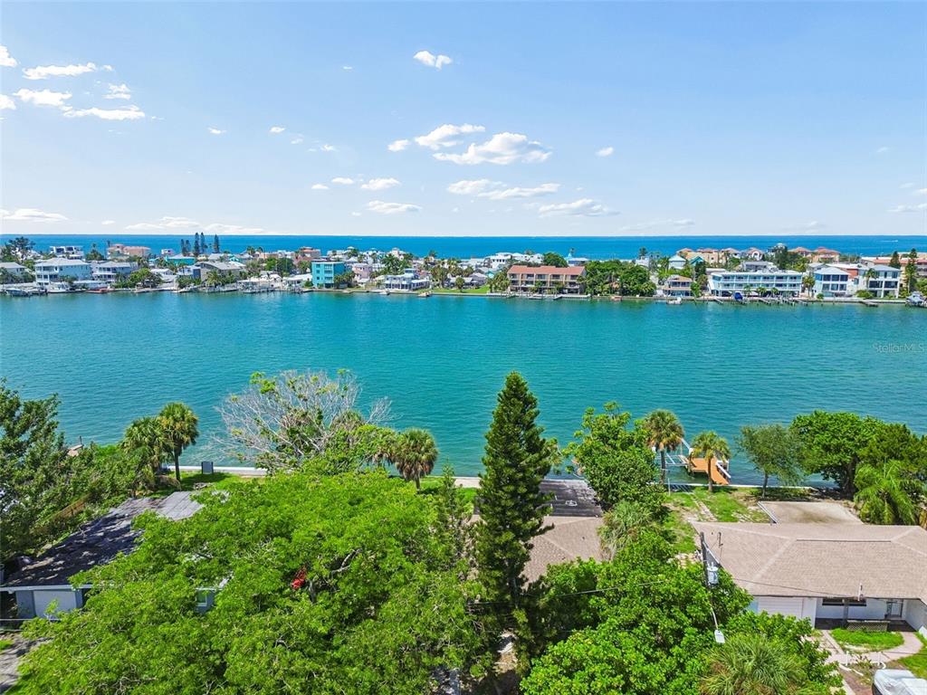 An elevated view of a waterfront property overlooking a bay with buildings on the horizon — 9300 GULF BOULEVARD, ST PETE BEACH, FL