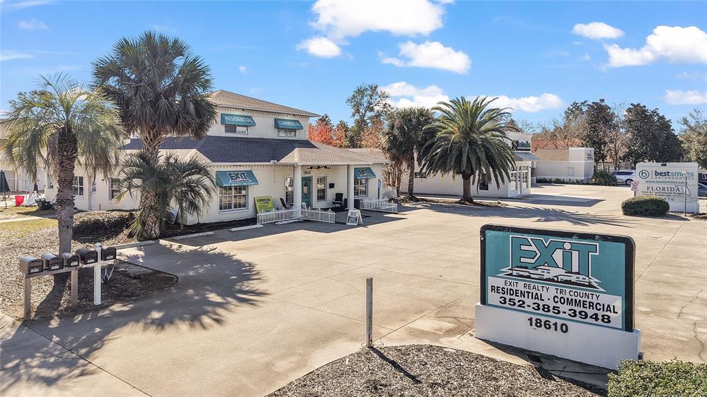 A commercial building with a large parking lot and a prominent real estate sign — 18610 US HIGHWAY 441, MOUNT DORA, FL