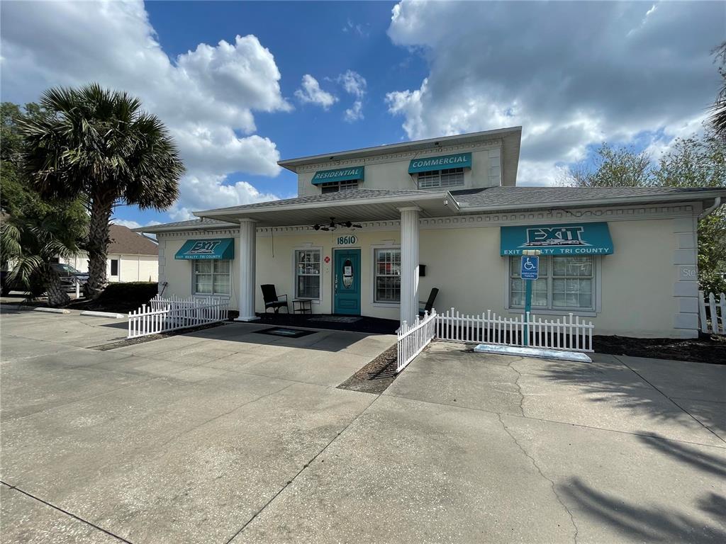 A two-story commercial building with a teal door, white columns, and blue awnings — 18610 US HIGHWAY 441, MOUNT DORA, FL