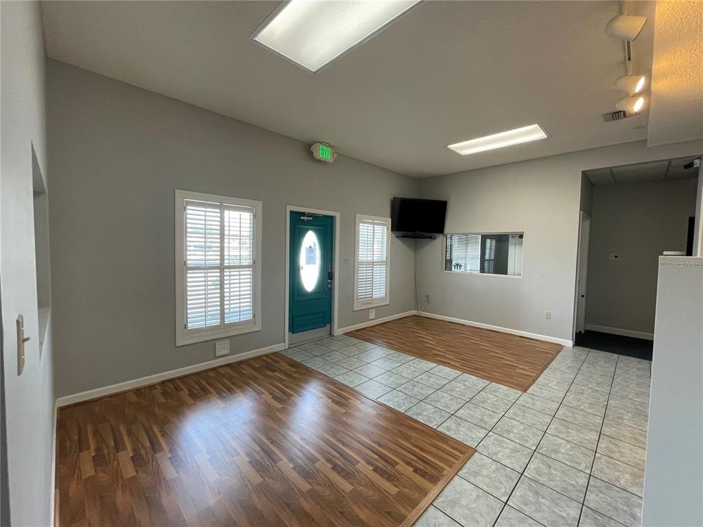 An office space features gray walls, wood-look flooring, tiled areas, and a teal entry door — 18610 US HIGHWAY 441, MOUNT DORA, FL