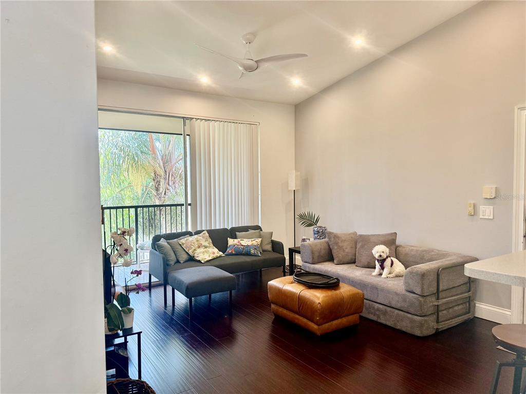 A living room features dark wood floors, two sofas, a leather ottoman, and a balcony — 1180 RESERVE WAY UNIT 302, NAPLES, FL