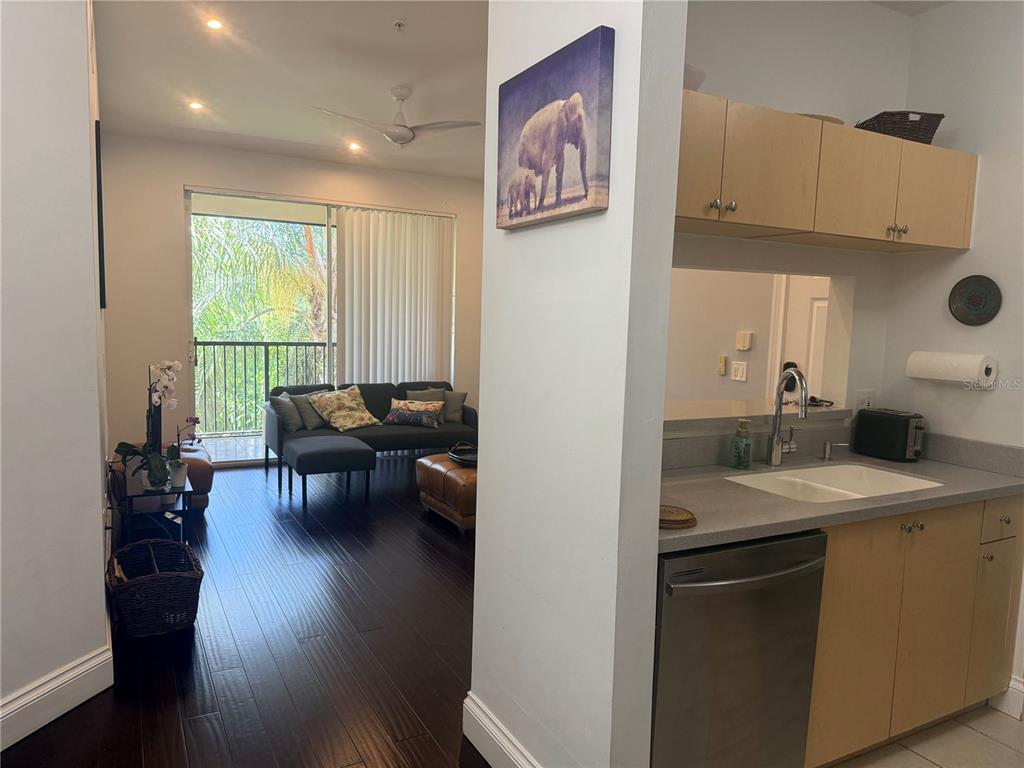 A view from a kitchen with light wood cabinets looking into a living room area — 1180 RESERVE WAY UNIT 302, NAPLES, FL