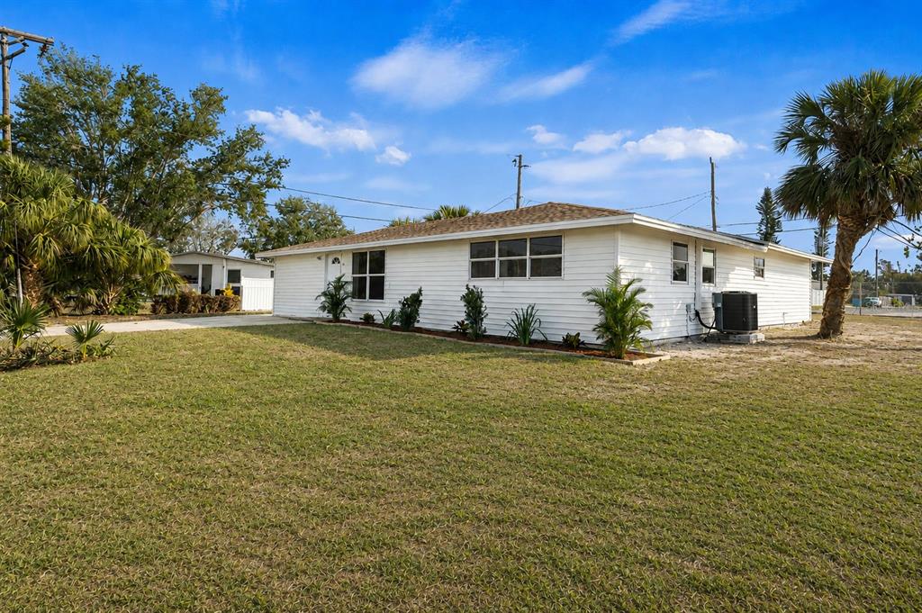 A white, single-story house with a lawn, palm trees, and an exterior air conditioning unit — 6211 CORNELL ROAD, BRADENTON, FL