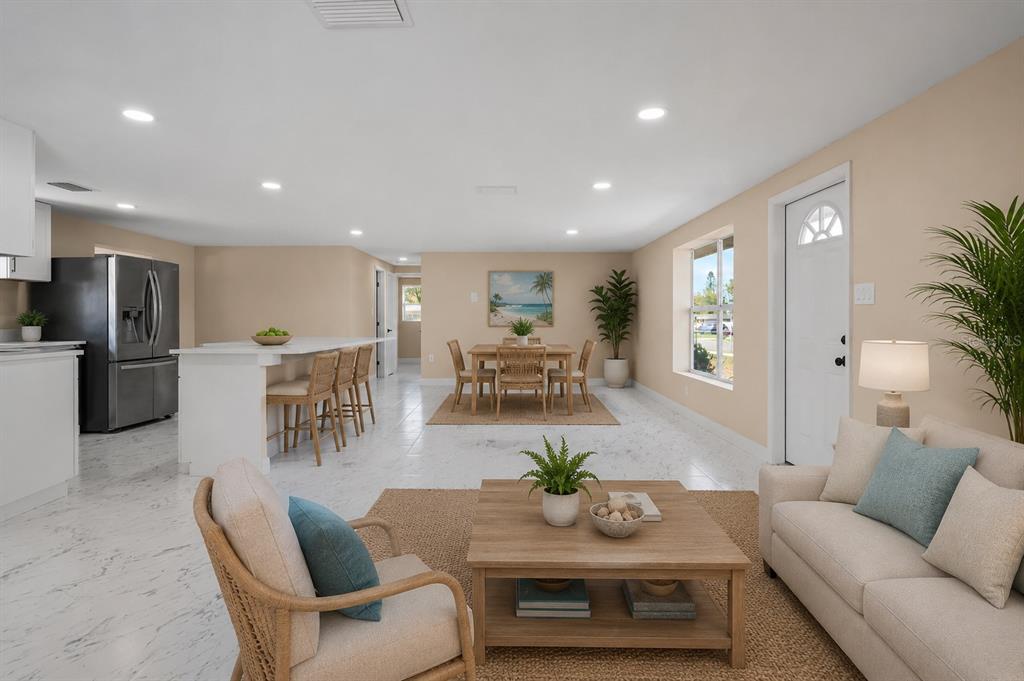 An open-concept living and dining area features white marble-look tile floors and neutral wall paint — 6211 CORNELL ROAD, BRADENTON, FL