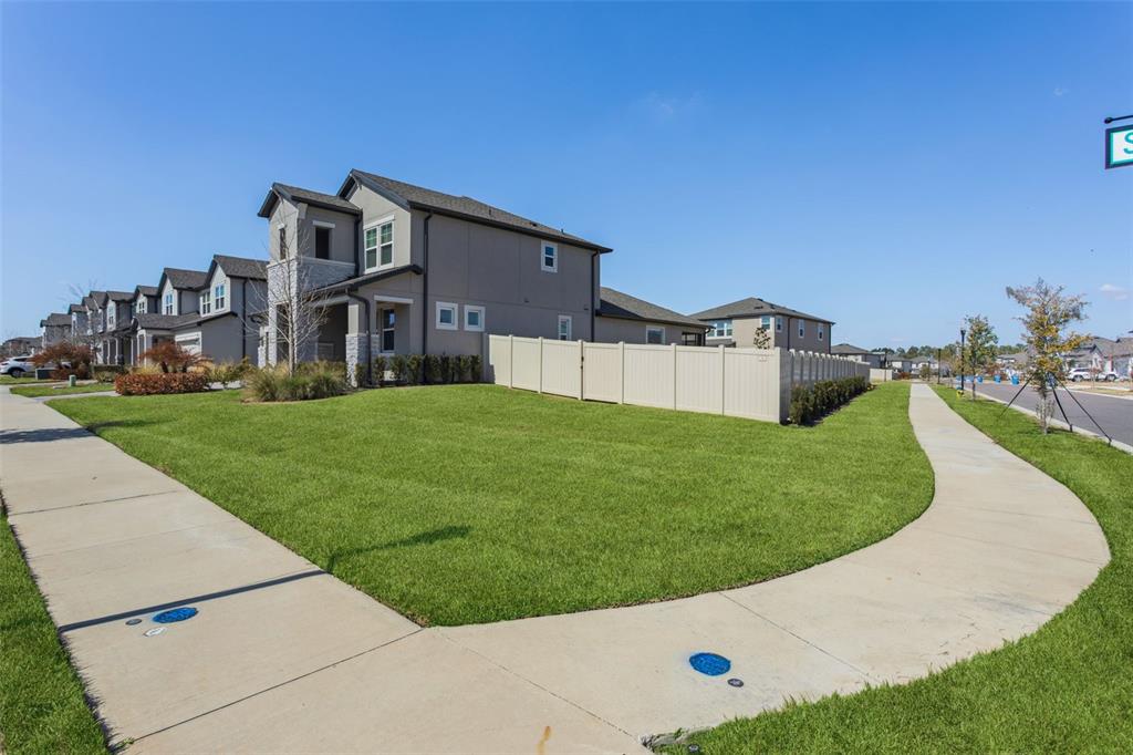 A row of two-story suburban houses with a vinyl fence and a concrete sidewalk — 33287 SYCAMORE LEAF DRIVE, WESLEY CHAPEL, FL