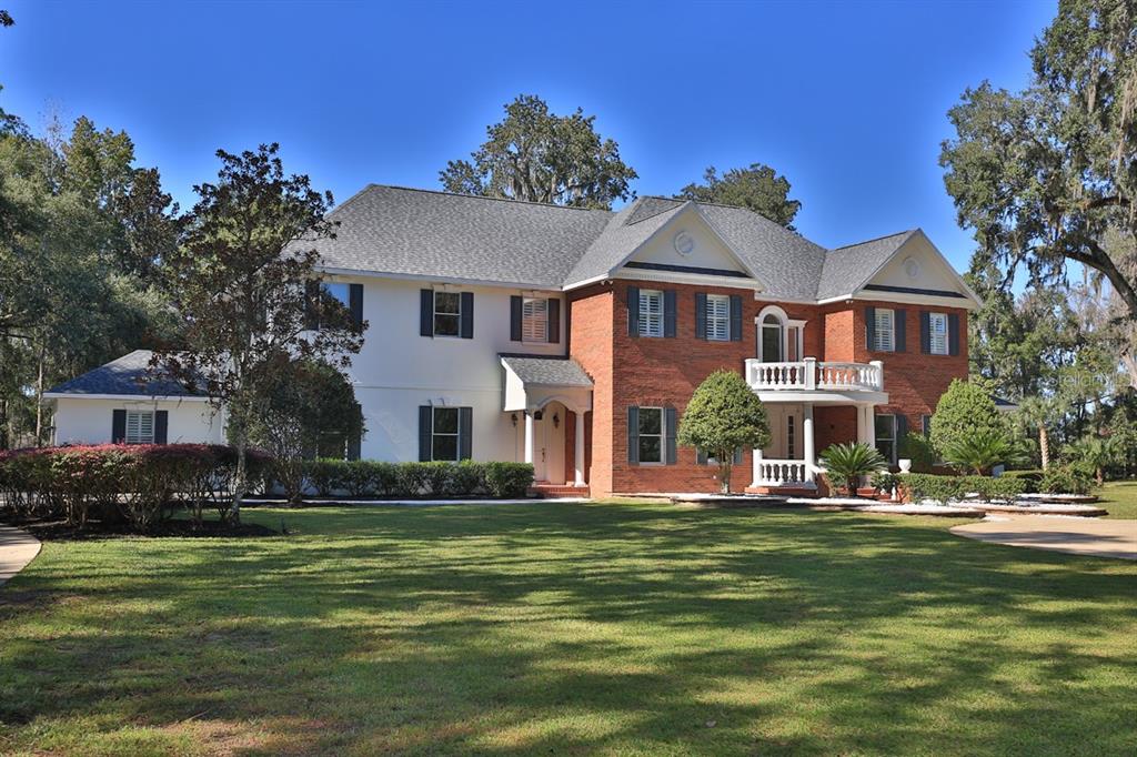 A two-story house features a brick and white exterior with a balcony and large lawn — 1401 SE 91ST PLACE, OCALA, FL
