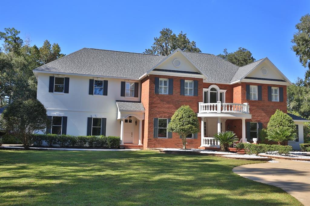 A two-story house with a brick and white exterior, a front balcony, and a lawn — 1401 SE 91ST PLACE, OCALA, FL