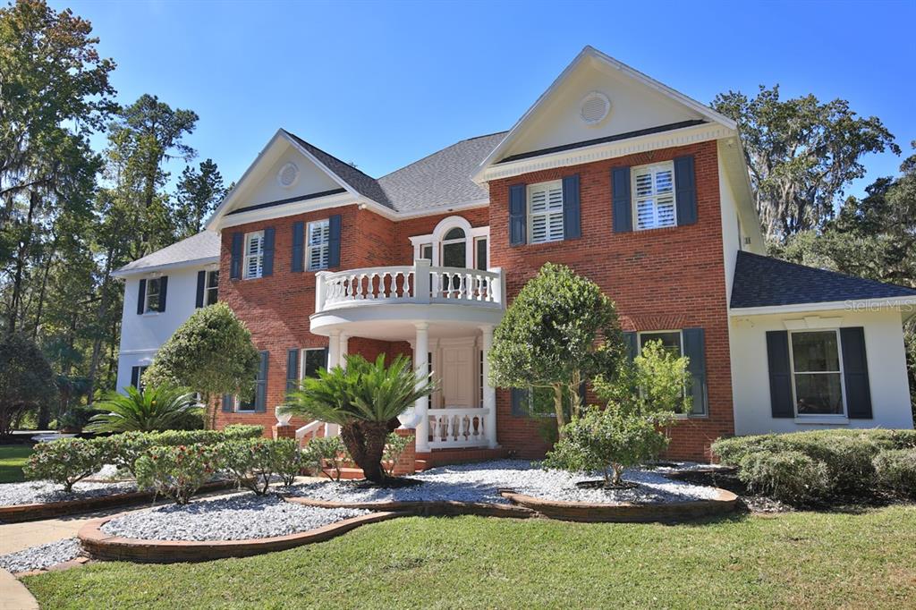 A two-story brick house features a prominent curved balcony above the front entrance — 1401 SE 91ST PLACE, OCALA, FL