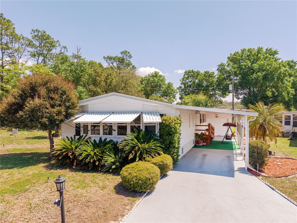 A single-story mobile home with a white exterior, metal awnings, and a covered carport — 2513 INDEPENDENCE LANE, ST CLOUD, FL
