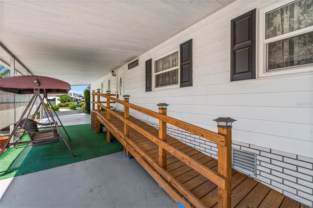 A wooden wheelchair ramp leads to the entrance of a white mobile home — 2513 INDEPENDENCE LANE, ST CLOUD, FL