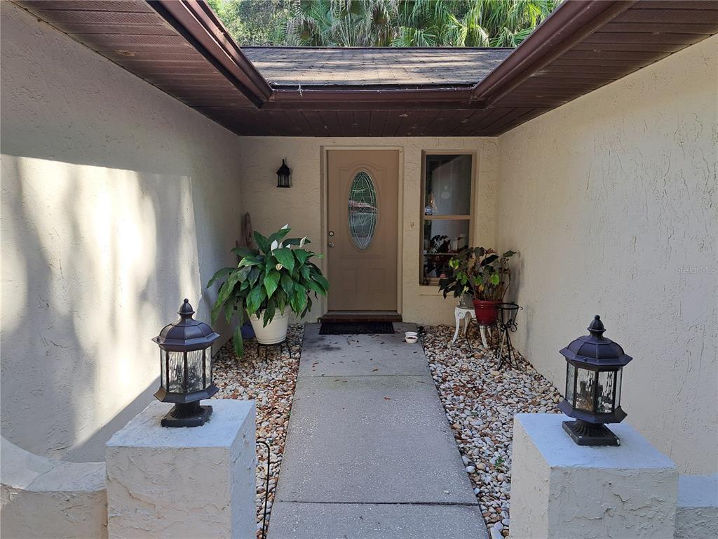 A concrete walkway leads to a tan front door flanked by two outdoor lanterns — 5672 AVE H, MC INTOSH, FL