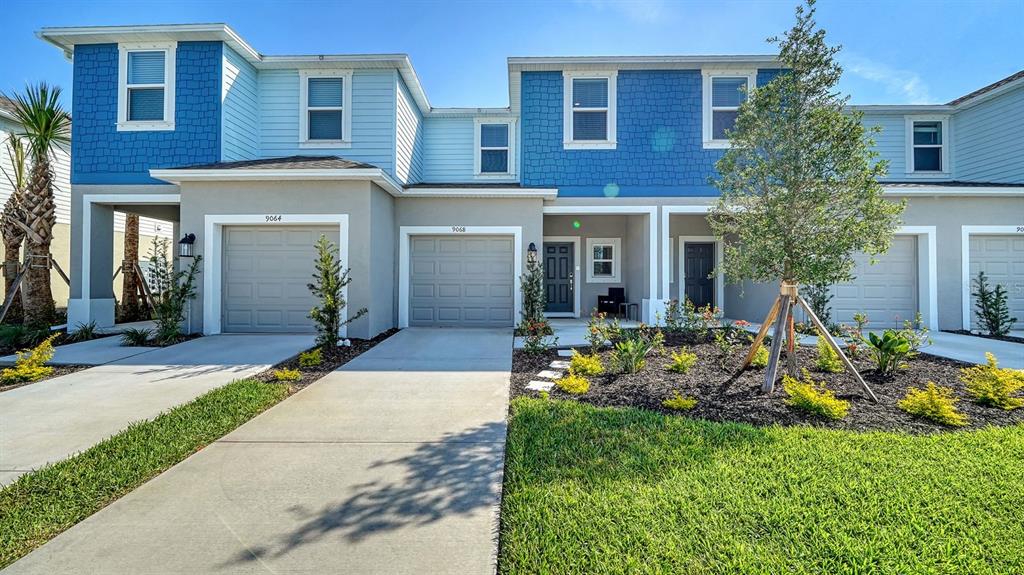 The exterior of a multi-unit townhouse complex features blue and gray siding with concrete driveways — 9068 DRIVEN SNOW STREET, SARASOTA, FL
