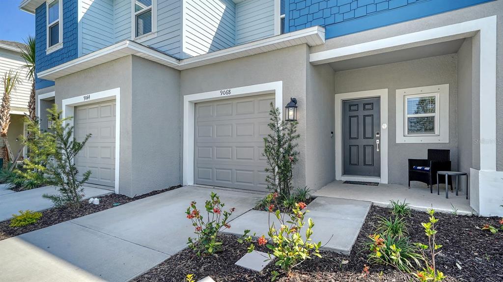 The exterior view shows a two-story townhouse with a gray garage, front door, and landscaping — 9068 DRIVEN SNOW STREET, SARASOTA, FL