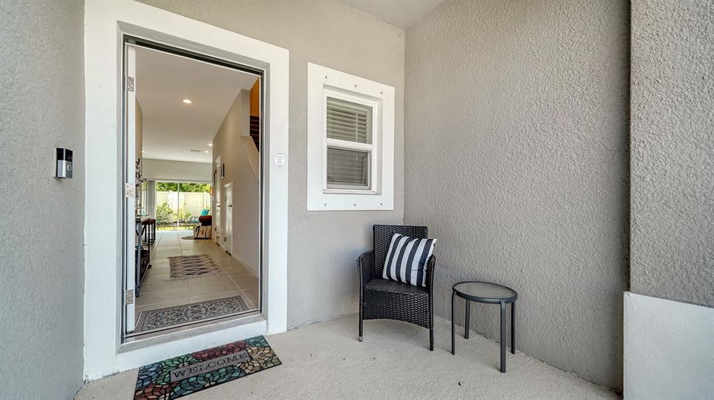 A covered entryway features a front door opening into a home with a small chair — 9068 DRIVEN SNOW STREET, SARASOTA, FL