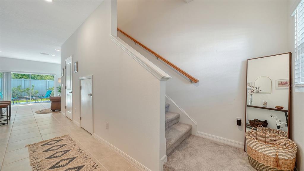 A staircase with carpeted steps and a wooden handrail sits beside a tiled entryway — 9068 DRIVEN SNOW STREET, SARASOTA, FL